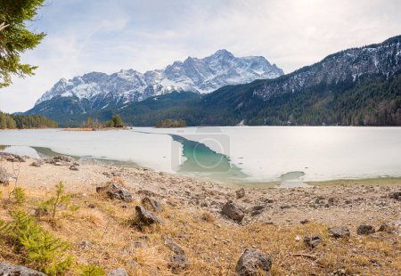 Téléchargez les photos : Lac Eibsee gelé avec petit canal. vue sur la masse de montagne de Zugspitze. paysage bavarois en mars - en image libre de droit
