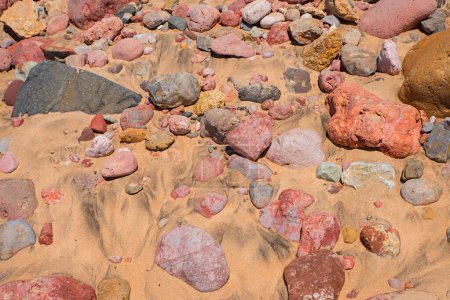 Bunte Sandsteinkies im sandigen Boden, Algarve-Strand