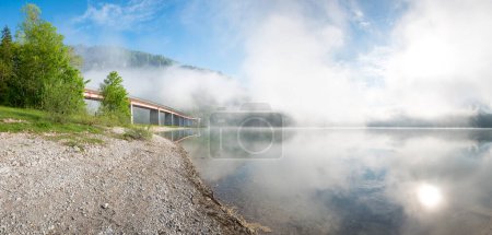 Nebel über dem Sylvensteinsee, Kiesstrand und Brücke, Frühlingslandschaft Oberbayern, blauer Himmel