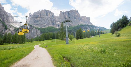 walkway from Colfosco to Pisciadu Waterfall, Dolomite Alps, south tyrol. idyllic spring landscape panorama with buttercups and wildflowers. way crossing the cable car to Grodner Joch.