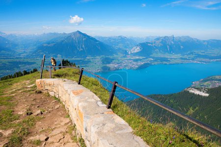 hiker at Niederhorn mountain summit, view to lake Thunersee and Bernese Alps, switzerland