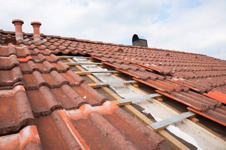 Photo for Partially uncovered house roof to replace the old roof tiles. two chimneys above - Royalty Free Image