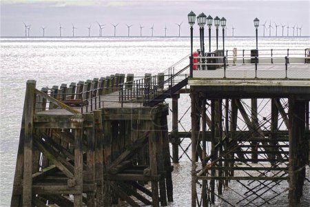 Photo for Wooden and cast iron pier at Worthing in West Sussex, England. With Rampion Windfarm in distance. - Royalty Free Image