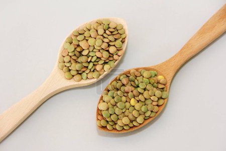 Photo for Small grains of natural green lentils in a wooden spoon on a gray background - Royalty Free Image