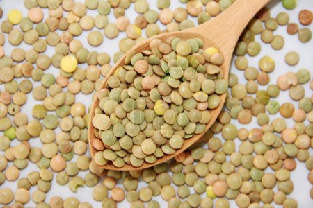 Photo for Small grains of natural green lentils in a wooden spoon on a gray background - Royalty Free Image