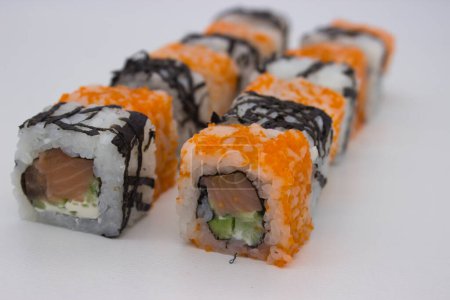 Das Bild zeigt einen dynamischen Winkel aus verschiedenen Sushi-Rollen in einer versetzten Formation, der den Kontrast zwischen den mit Masago überzogenen kalifornischen Rollen und dem einfachen, mit Algen umwickelten Sushi unterstreicht. Der orangefarbene Masago verleiht der Haut eine helle, kaviarartige Textur.