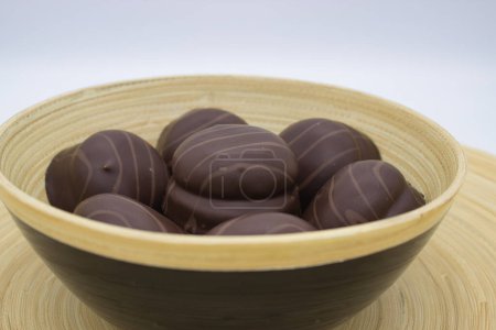 Élégants chocolats belges rayés dans un bol en bambou