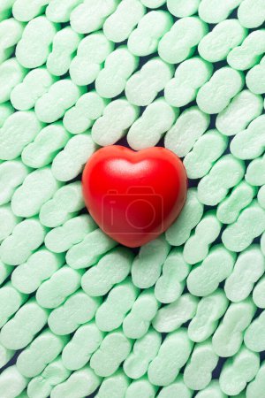 Tiefrotes Herz auf grünen Styroporteilen, geordnet angeordnet. Konzept des Herzschutzes und der allgemeinen Gesundheit.