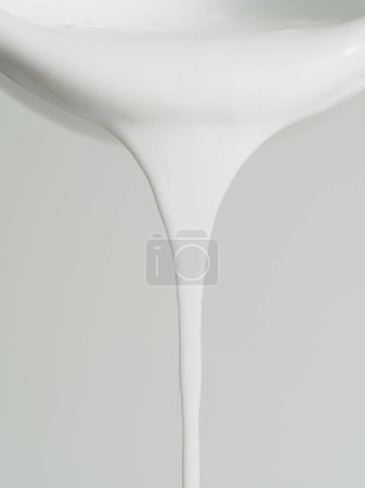 Goteo simétrico de pintura blanca en el borde de un tazón, sobre un fondo blanco.