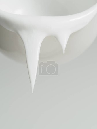 Photo for High resolution image capturing white paint dripping down from the rim of a white ceramic bowl. - Royalty Free Image