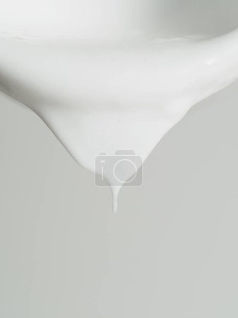 Ein detailliertes Bild zeigt einen winzigen Tropfen weißer Farbe, der am glatten Rand einer weißen Schüssel hängt.