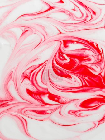 Abstraktes Muster aus roter und weißer Farbe wirbelt, wodurch eine Textur entsteht, die an geschmolzenes Erdbeer- und Sahneeis erinnert.