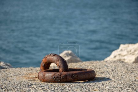 Téléchargez les photos : Anneau d'amarrage pour bateau rouillé sur un brise-lames avec la mer en arrière-plan - en image libre de droit