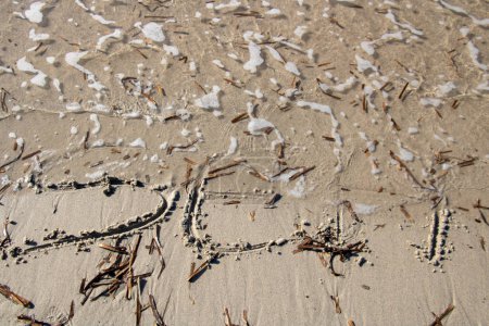 Téléchargez les photos : Vague effaçant le mot mer écrit sur la plage dans le sable - en image libre de droit