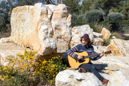 Téléchargez les photos : Fte de la musique 21 juin - Fête dans une vieille carrière de pierre avec un jeune homme portant un chapeau Borsalino jouant de la guitare folk - en image libre de droit