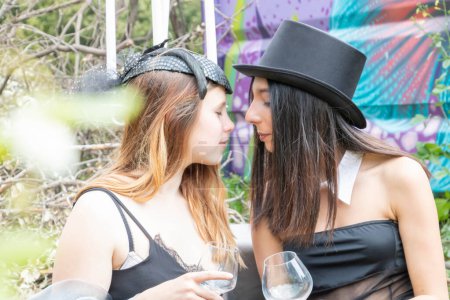 Téléchargez les photos : Deux femmes très élégantes en tenue Steampunk avec chapeau haut de forme et voile Fascinateur dans un jeu de séduction - Femmes lesbiennes multiraciales et multiethniques - en image libre de droit