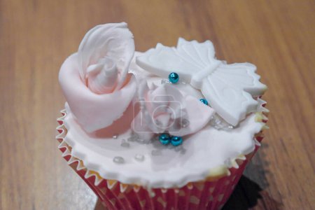 Téléchargez les photos : Cupcake pour baptême ou mariage dans les tons blanc, rose et bleu avec une garniture en pâte de sucre sculpté dans la fleur et l'arc - en image libre de droit