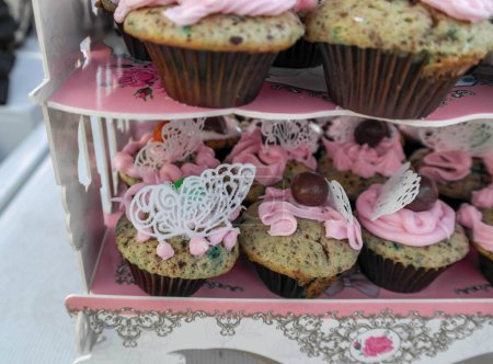 Téléchargez les photos : Plusieurs couches de cupcakes sur un stand de gâteau avec décoration en sucre glace, dentelle de sucre, glaçage et garniture - en image libre de droit