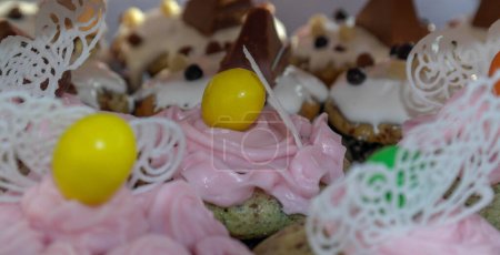 Foto de Primer plano de un surtido de cupcakes, glaseado real, encaje de azúcar, chispas de chocolate y cacahuete cubierto de chocolate. - Imagen libre de derechos