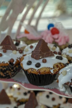 Téléchargez les photos : Pièce d'une barre de chocolat en forme de pyramide, sur glaçage royal blanc sur un cupcake - en image libre de droit