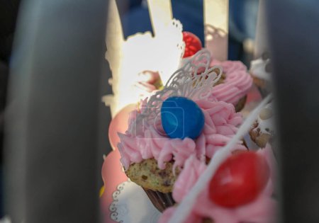 Téléchargez les photos : Cupcake vu de l'extérieur d'un stand de gâteau, glaçage royal rose, papillon en dentelle de sucre et cacahuète recouverte de chocolat - en image libre de droit