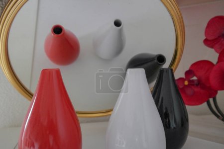 Téléchargez les photos : Reflet de 3 vases, rouge, blanc et noir dans un miroir avec une orchidée rouge - en image libre de droit