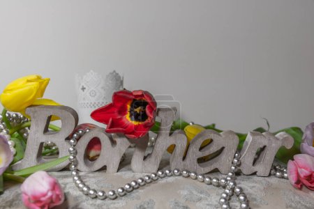 Auf Französisch geschriebenes Wort Glück (bonheur is Happiness) in Holz geschnitzt, umgeben von Tulpen und einer Kette aus grauen Perlen auf einem Hocker im Boudoir von Madame