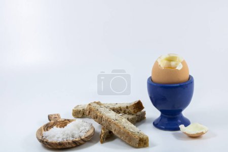 Boiled egg in blue egg cup with his country bread soldiers with cheese and celery salt