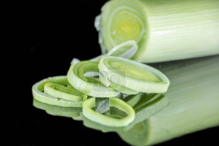 Photo for The green of a leek stalk partially sliced on a black background with mirror effect and their reflections - Royalty Free Image