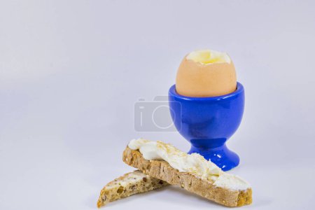 Foto de Huevo cocido en taza de huevo azul con sus soldados de pan de campo con queso y sal de apio - Imagen libre de derechos