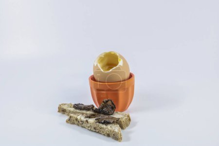 Boiled egg in an egg cup with orange bread buttered bread fingers campaign and black truffle slices