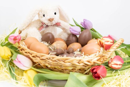 Foto de Conejo de Pascua en un nido con tulipanes y huevos de Pascua - Imagen libre de derechos