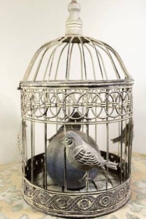 Vintage metal bird cage with chiseled birds and a candle in the cage