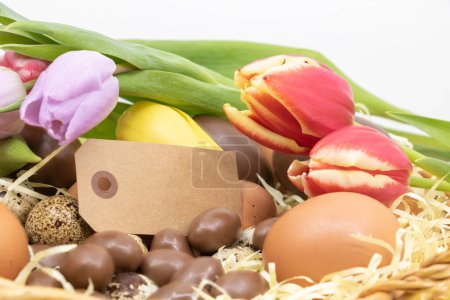 Foto de Etiqueta, huevos de chocolate, huevos de codorniz y huevos de pollo y tulipanes para Pascua - Imagen libre de derechos