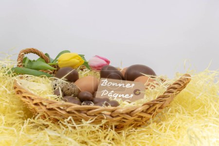 Happy easter (Bonnes Pques is Happy Easter writing in french) on a label, easter celebration with chocolate eggs and pastel tulips
