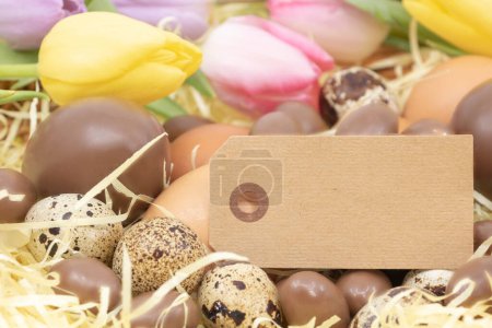 Foto de Etiqueta, huevos de chocolate, huevos de codorniz y huevos de pollo y tulipanes para Pascua - Imagen libre de derechos