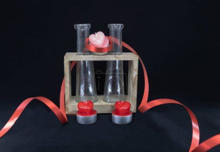Téléchargez les photos : Cadeau romantique un vase en verre et en bois, un ruban cadeau et des bougies en forme de coeur - en image libre de droit