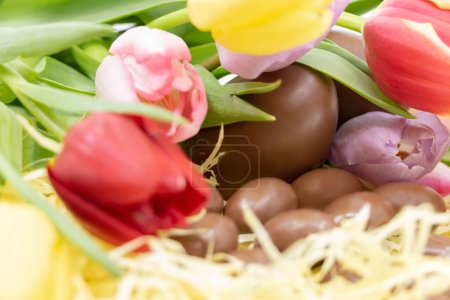Ostern mit sanften Farben und Pastell mit Schokoladeneiern und Tulpen