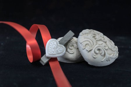 3 corazones en cerámica blanca y una cinta de regalo sostenida por una pinza
