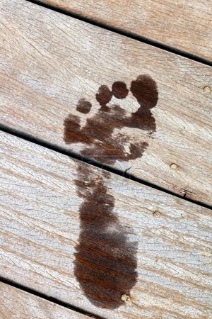 Fußabdruck nass auf einem Holzponton pro Hitzetag im Sommer - heiße Ferien