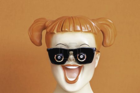 Téléchargez les photos : Visage d'une adolescente rousse souriante sur fond orange avec des cheveux attachés dans une couette portant des lunettes avec caméra intégrée - nouvelle technologie - en image libre de droit