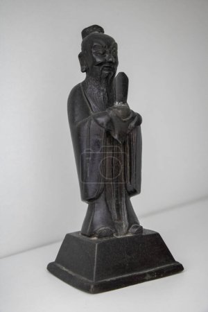 schwarze chinesische Bronzestatuette im Profil auf weißem Hintergrund, ausgeschnittenes Objekt