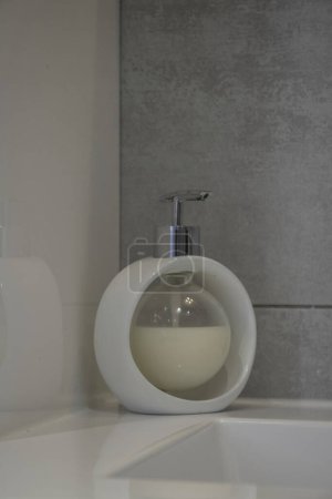 Bubble liquid soap dispenser, white on a washbasin rim, cut-out object