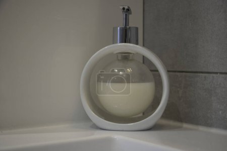 Bubble liquid soap dispenser, white on a washbasin rim, cut-out object