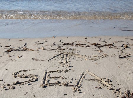 Téléchargez les photos : Le mot mer écrit (en anglais) dans le sable avec une flèche pointant vers la mer - en image libre de droit