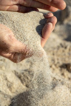 Hand des Menschen, die eine Handvoll Sand fallen lässt - Konzeptfreiheit, loslassen, was die Zeit vergeht