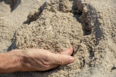 main mâle attrapant une poignée de sable