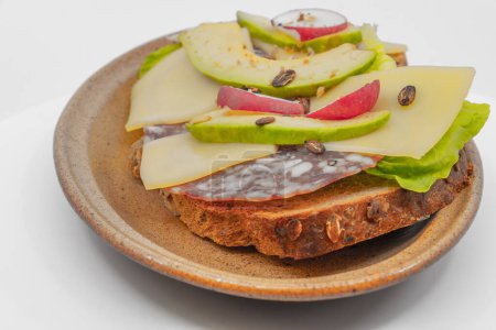 Photo for Full Sandwich with avocado and radish slices on sheep cheese slices and sausage on a slice of bread grain assiete - Royalty Free Image