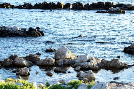 Téléchargez les photos : Paysage de bord de mer en hiver au lever du soleil avec des teintes froides et la lumière du pâturage sur les rochers - en image libre de droit