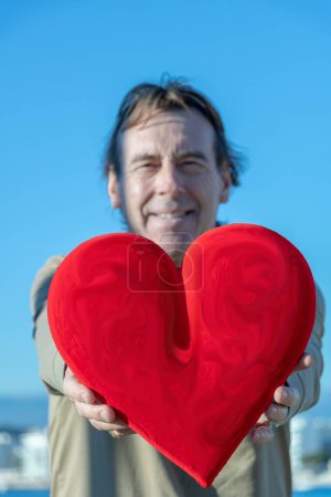 Foto de Hombre sosteniendo un enorme corazón rojo delante de él - Imagen libre de derechos